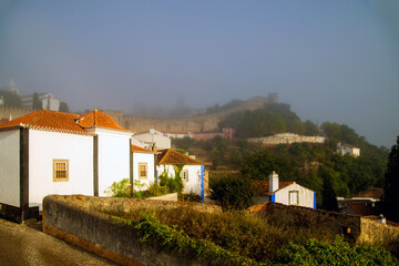 Fototapeta na wymiar View of the old part of Obidos, Portugal in the early foggy morning