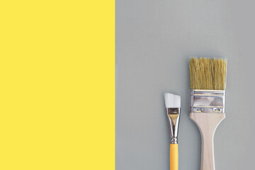 Two paint brushes on yellow and grey background. Colors of the 2021 year.
