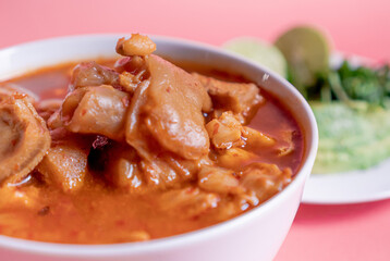 Exquisite Mexican Menudo on a white plate accompanied by a dish with condiments on the back.