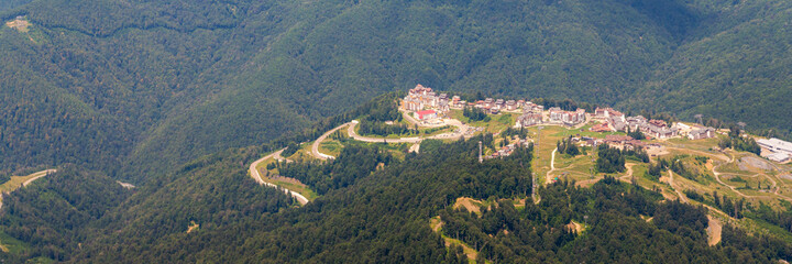 Fototapeta na wymiar Top view of resort town with hotels on background of mountains. Beautiful landscape of hotels located in mountains in summer