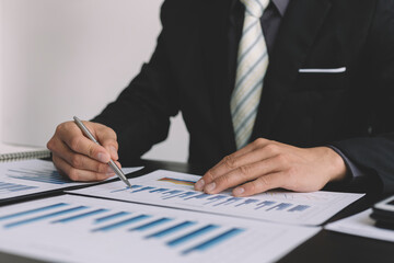 Business men are analyzing and evaluating marketing for a company using graphs on their desks in the office Concept of business risk analysis and assessment