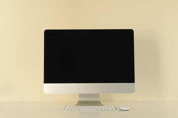 Blank screen desktop computer against beige background