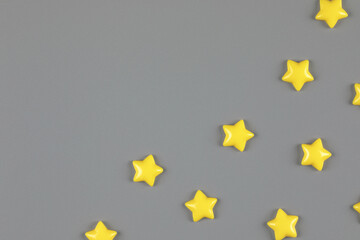 Cute yellow decorative stars sparse on neutral gray background with copy space for text. Top view, flat lay composition for mock up template design. Year color trend concept.