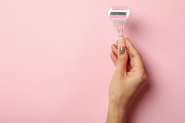 Female hand hold razor on pink background, space for text