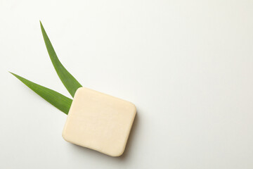 Piece of natural soap and leaves on white background