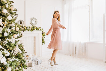 Beautiful cheerful happy young girl with christmas gifts on the background of a new year tree at home