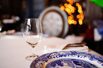 an empty glass of wine and a plate with a blue pattern on the table.