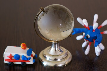 Toy ambulance next to the globe. Next to the figure of the virus.
