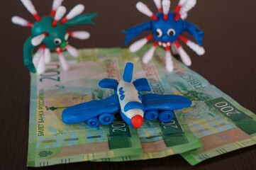 The figure of the virus on banknotes. Near a toy plane.