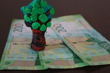 Toy tree made of plasticine on banknotes. Financial symbol.