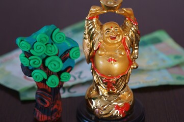Figure of the Golden Buddha on the table. There is a toy tree nearby.