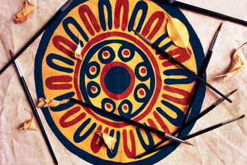 Some paint brushes and leaves on a circular mandala. Spending days indoors, indoor activities, creating art.