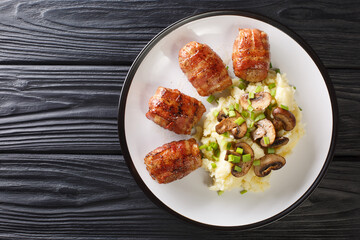 Slavink is a traditional Dutch dish consisting of meat that is wrapped in bacon and fried served with mashed potatoes and mushrooms closeup in the plate on the table. horizontal top view from above