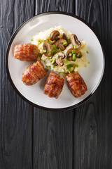 Dutch Slavinken is an excellent comfort food cooked of ground meat wrapped in bacon served with mashed potatoes and mushrooms closeup in the plate. vertical top view from above