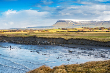 Rosses point beach and Benbulben flat top mountain covered in snow in county Sligo, Ireland, Warm...