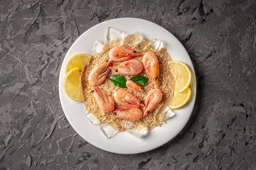 A plate with a frozen ready made dish of rice and shrimp with lemon on a black table. Concept of a delicious food, like in a restaurant, that can be prepared fast