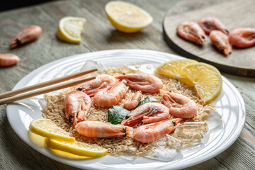 Appetizing delicious frozen dish of shrimps and rice with lemon on a wooden table. Concept of ready made frozen food for dinner like in a restaurant at home