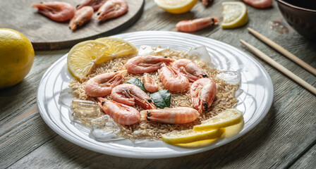 Appetizing delicious frozen dish of shrimps and rice with lemon on a wooden table. Concept of ready made frozen food for dinner like in a restaurant at home