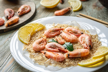 Appetizing delicious frozen dish of shrimps and rice with lemon on a wooden table. Concept of ready made frozen food for dinner like in a restaurant at home