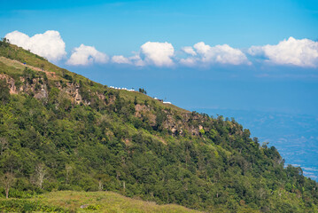 Fototapeta na wymiar Mountain view morning on top hills and green forest cover with soft mist and blue sky background.Thailand.
