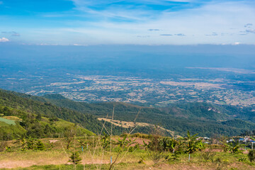 Fototapeta na wymiar Mountain view morning on top hills and green forest cover with soft mist and blue sky background.Thailand.