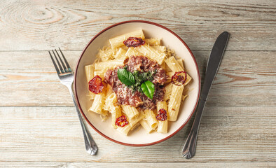 Plate of delicious appetizing vegetarian pasta with tomato sauce, tomatoes, cheese and basil on a wooden table. Top view