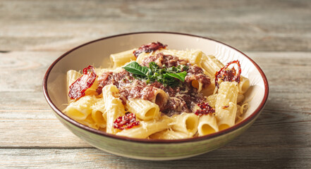 Plate of delicious appetizing vegetarian pasta with tomato sauce, tomatoes, cheese and basil on a wooden table