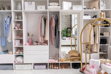 Modern white wardrobe with stylish spring clothes and accessories. Large wardrobe with various clothes