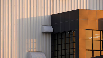 Perspective side view of beautiful golden sunlight on surface of brown modern office on white corrugated metal wall of industrial building in evening time