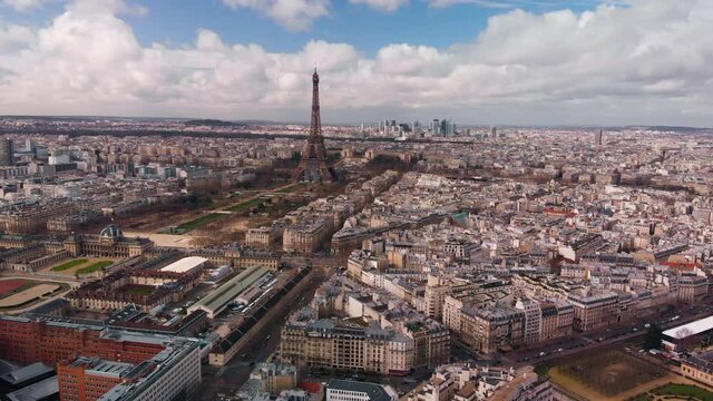Eiffel Tower aerial footage. Eiffel Tower, &Eacute;cole Militaire, Champ de Mars in early spring with the blue sky covered with white clouds. Camera reveals the army museum and St Francis Xavier's Church