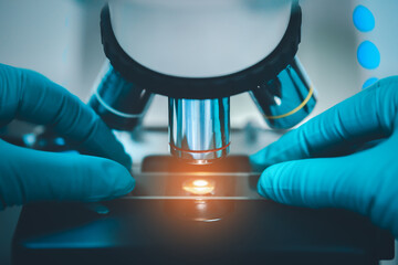 Close up of Scientist hands with microscope in medical research lab or science laboratory.