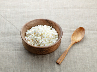 curd in a wooden bowl with spoon on canvas background