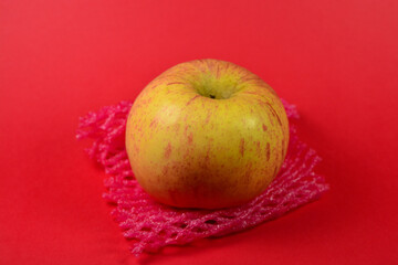 Close up Fresh apples with a layer of net mesh on a red background. organic apples