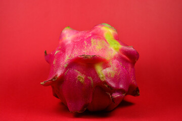 Fresh dragon fruit that is still intact on a red background