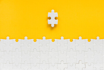 Top view of a piece of jigsaw puzzle isolated from the rest on yellow background.