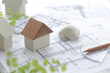 木でできた家の模型とマイホームの設計図のイメージ