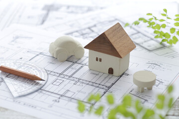 木でできた家の模型とマイホームの設計図のイメージ