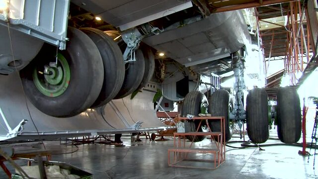 Maintenance of landing gear of the Il-76 aircraft. Chassis doors open. Landing gear legs rise into niche. Chassis doors close. Close-up. Plane is on hydraulic lifts.