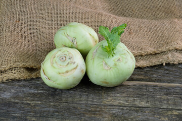 Drei Kohlrabi / Kohlgemüse auf einem rustikalen (bäuerlichen) Hintergrund aus altem Holz und...