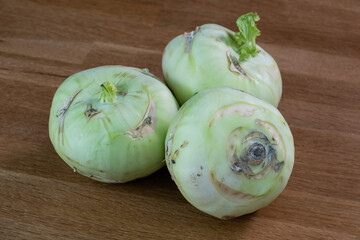 Drei Kohlrabi / Kohlrüben liegen auf einem Hintergrund aus Holz