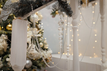 Soft focused shot of beads and artificial icicles on fir tree and golden shiny Christmas lights bokeh background. Festive atmosphere, holiday spirit, New Year celebration concept.