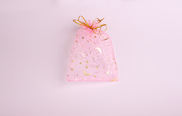 This is a beautiful gift of transparent pink and gold color empty Voile packing bag on a pink background. Suitable for packaging jewelry, cosmetics, small gifts and surprises.