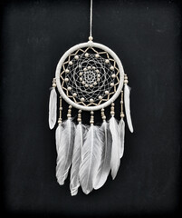 Beautiful handmade boho styled dreamcatcher with white feathers and beads against black.