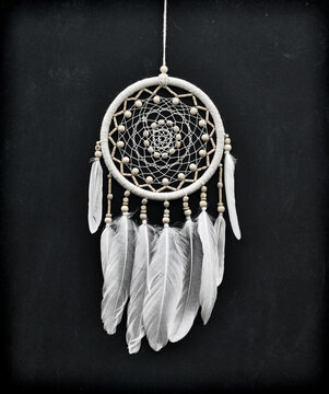 Beautiful handmade boho styled dreamcatcher with white feathers and beads against black.