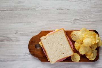 Homemade Bologna and Cheese Sandwich on a rustic wooden board on a white wooden background, overhead view. Flat lay, top view, from above. Copy space. © Liudmyla