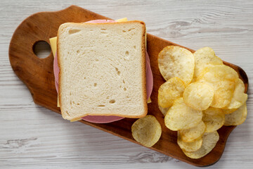 Homemade Bologna and Cheese Sandwich on a rustic wooden board on a white wooden table, overhead view. Flat lay, top view, from above.