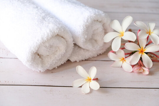 A white towel is placed on the table, with flowers on its side.