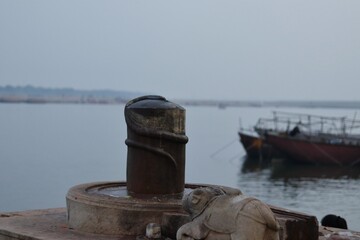 Shiva Lingam of Lord Shiva (Indian God) decorated with garlands and zendu flowers in a temple of Varanasi. Closeup shot of old decorated Shiva Lingam with selective focus near river Ganges.