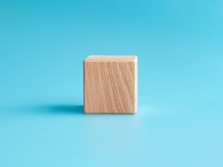 Wooden cube on blue background with space for text