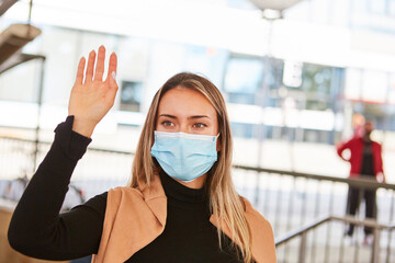 Waving woman as a passer-by with face mask in the city